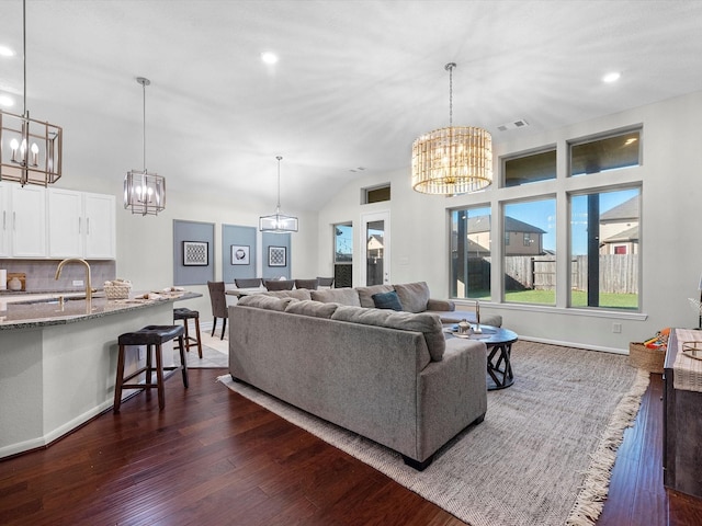 living room featuring vaulted ceiling, sink, a chandelier, and dark hardwood / wood-style flooring