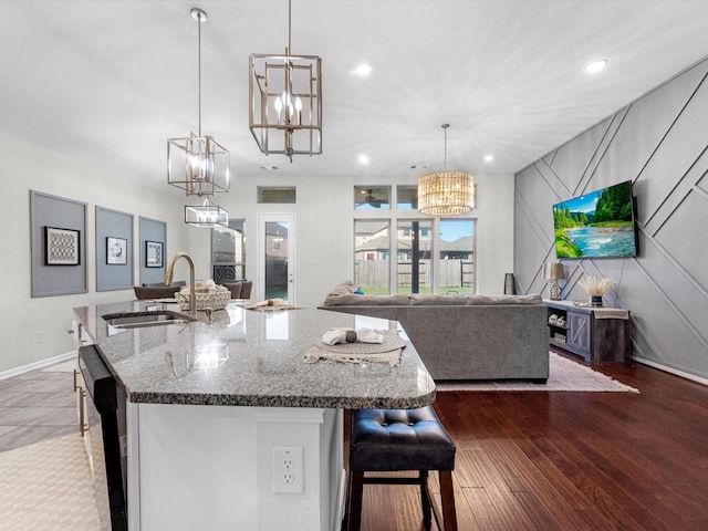 kitchen featuring dark stone countertops, sink, decorative light fixtures, and a kitchen island with sink