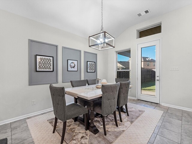 dining area featuring a notable chandelier, light tile patterned floors, and vaulted ceiling