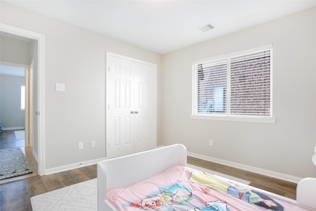 bedroom with dark wood-type flooring and a closet