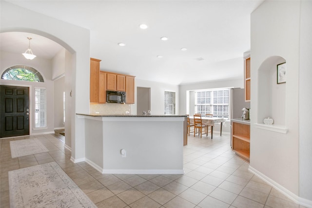 kitchen with decorative backsplash, kitchen peninsula, and light tile patterned flooring