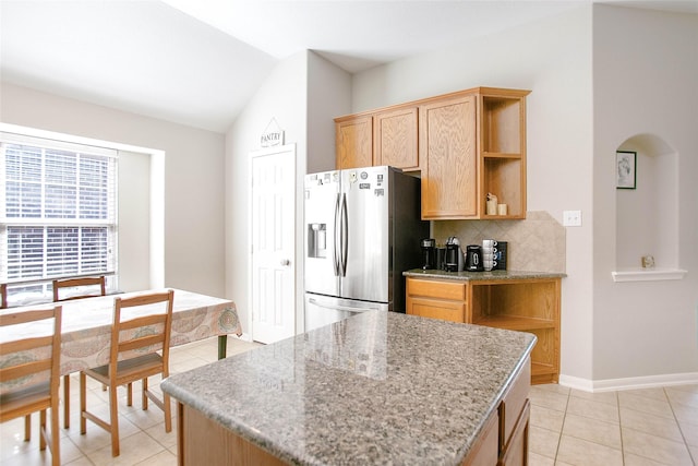 kitchen featuring lofted ceiling, backsplash, light tile patterned floors, stainless steel fridge with ice dispenser, and light stone countertops