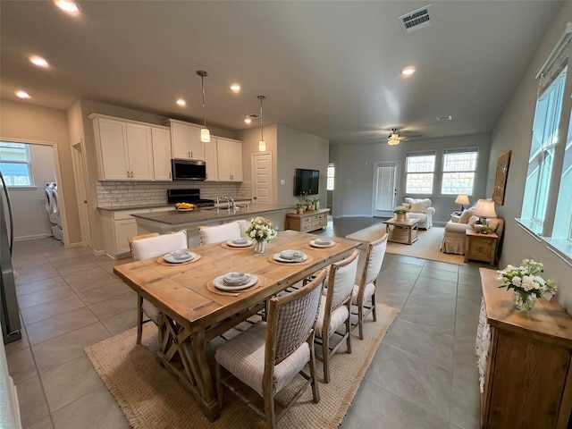 tiled dining space with plenty of natural light, ceiling fan, and washing machine and clothes dryer