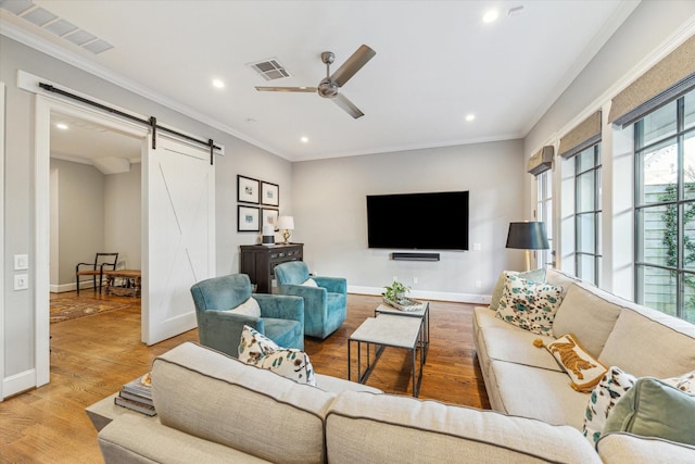 living room featuring crown molding, ceiling fan, a barn door, and hardwood / wood-style flooring