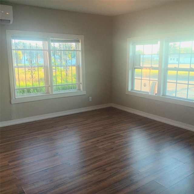 empty room with a wall mounted air conditioner, dark hardwood / wood-style flooring, and plenty of natural light