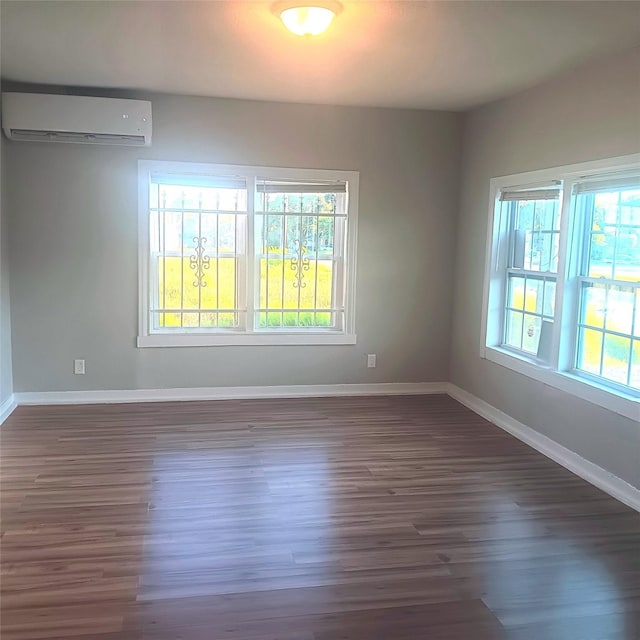 spare room with a wall mounted air conditioner and dark hardwood / wood-style floors