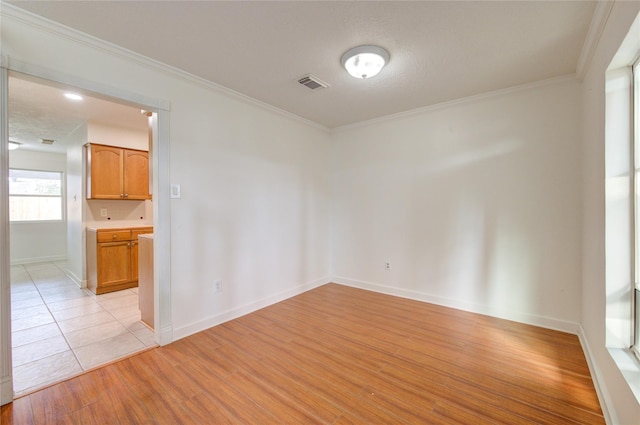 spare room featuring crown molding and light wood-type flooring