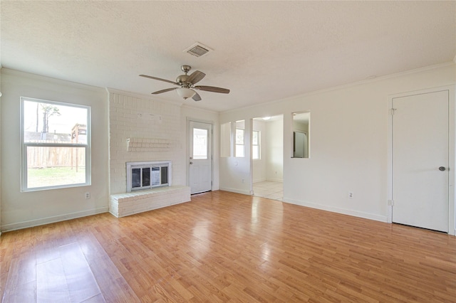 unfurnished living room with a brick fireplace, plenty of natural light, and light hardwood / wood-style floors