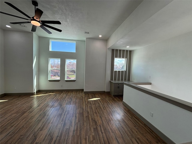 unfurnished room with a healthy amount of sunlight, dark hardwood / wood-style floors, and a textured ceiling