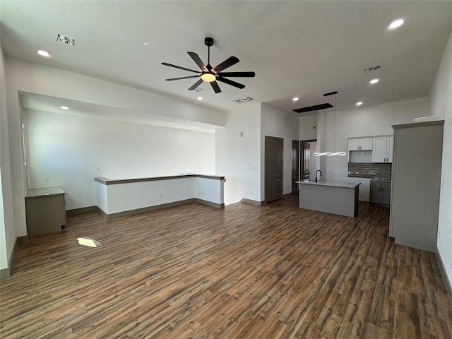 unfurnished living room featuring ceiling fan, dark hardwood / wood-style flooring, and sink