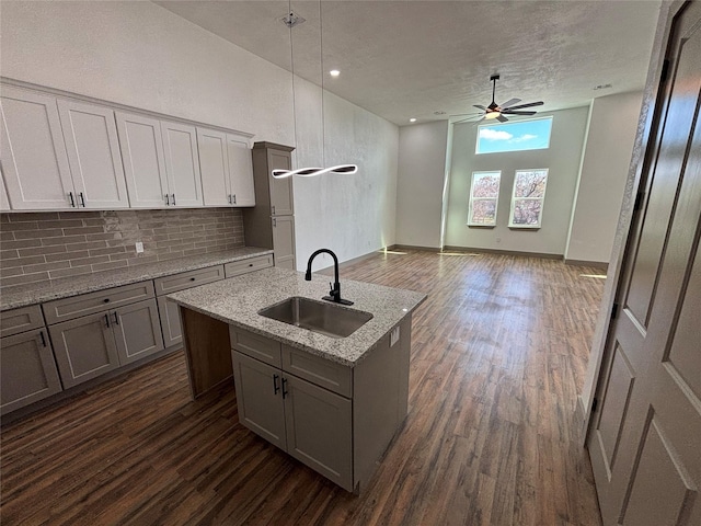 kitchen featuring dark hardwood / wood-style floors, a kitchen island with sink, sink, and hanging light fixtures