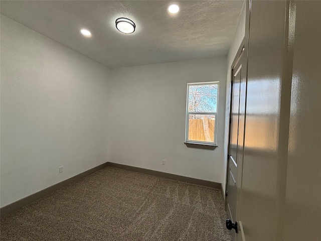 unfurnished room with dark colored carpet and a textured ceiling