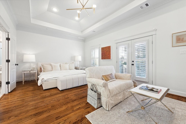 bedroom featuring a notable chandelier, access to exterior, a raised ceiling, dark wood-type flooring, and french doors