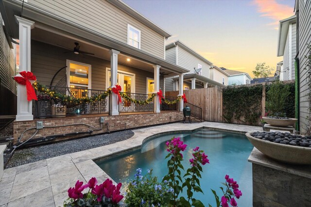 pool at dusk featuring ceiling fan