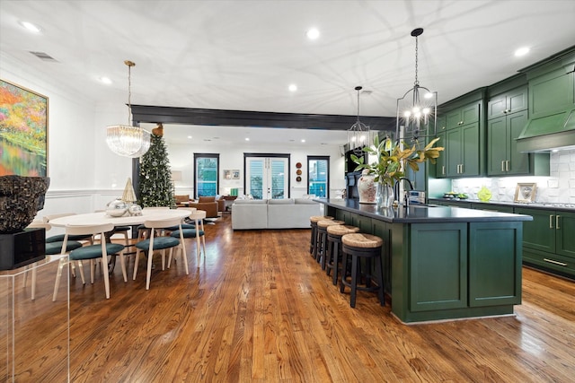 kitchen with a center island with sink, green cabinets, an inviting chandelier, and decorative light fixtures