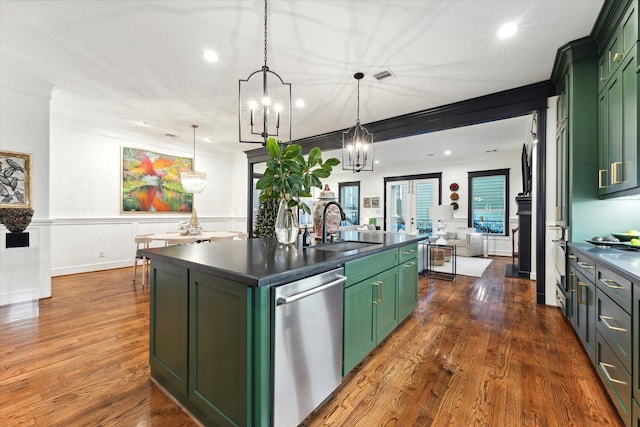 kitchen featuring sink, stainless steel appliances, green cabinetry, and a center island with sink