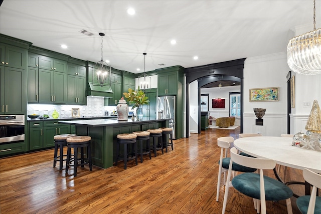 kitchen featuring stainless steel appliances, decorative light fixtures, green cabinets, and a kitchen island