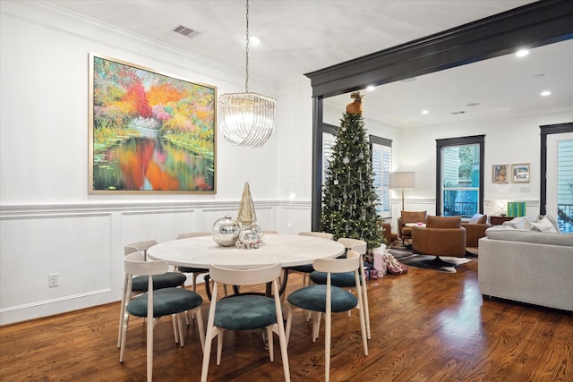 dining area featuring dark wood-type flooring, crown molding, and a chandelier