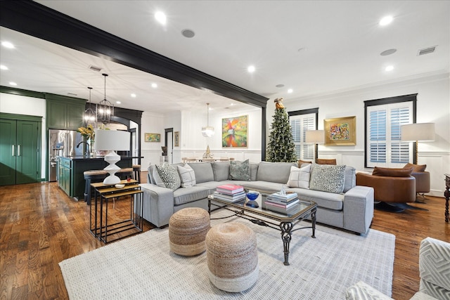 living room with crown molding, dark wood-type flooring, and a chandelier