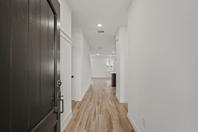 corridor featuring light wood-style floors, baseboards, visible vents, and recessed lighting