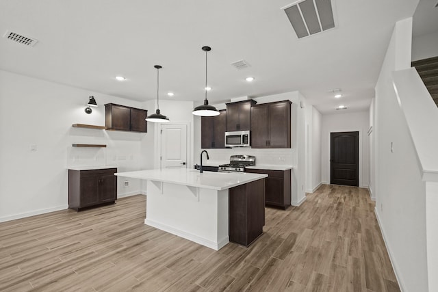 kitchen with visible vents, stove, dark brown cabinets, and stainless steel microwave