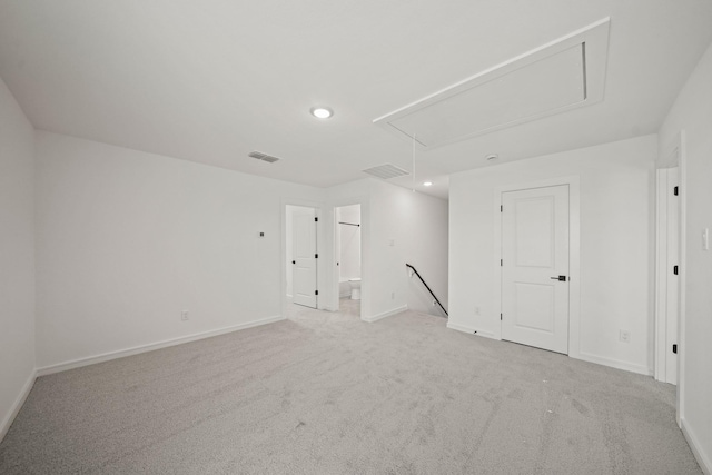 empty room featuring attic access, carpet, visible vents, and baseboards