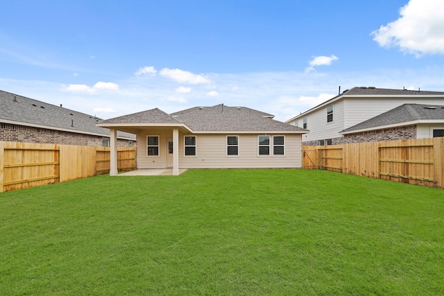 back of house featuring a patio, a lawn, a fenced backyard, and roof with shingles