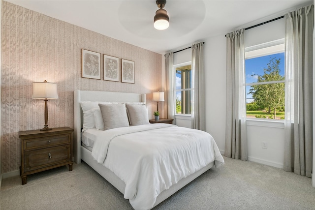 bedroom featuring multiple windows, light colored carpet, and wallpapered walls