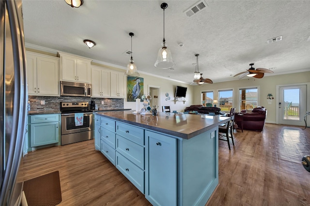 kitchen featuring dark hardwood / wood-style floors, appliances with stainless steel finishes, a kitchen island, and hanging light fixtures