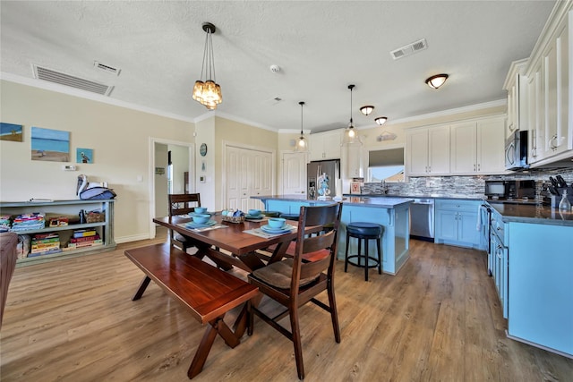 dining space with sink, crown molding, light hardwood / wood-style flooring, a textured ceiling, and a chandelier