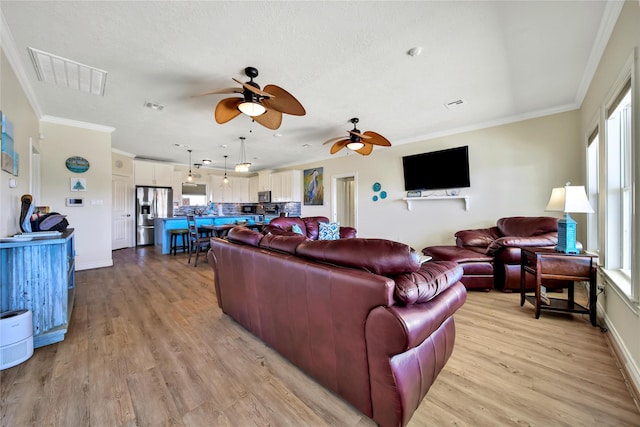 living room with crown molding, a wealth of natural light, and light hardwood / wood-style floors