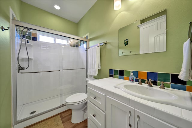 bathroom featuring a shower with door, vanity, hardwood / wood-style floors, and toilet