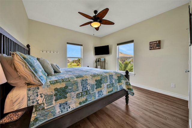 bedroom featuring ceiling fan, hardwood / wood-style floors, and multiple windows