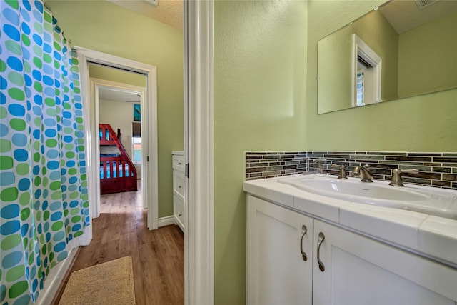 bathroom featuring vanity, backsplash, and wood-type flooring