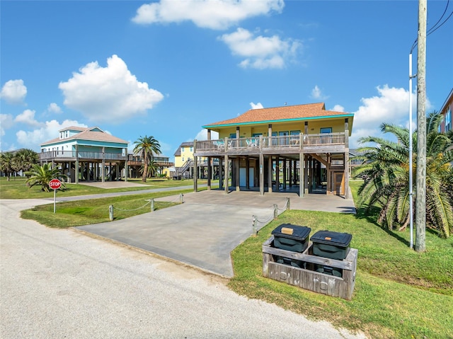 raised beach house with a carport, a porch, and a front lawn