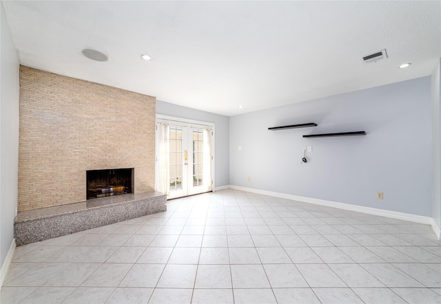 unfurnished living room with a large fireplace, light tile patterned floors, and french doors