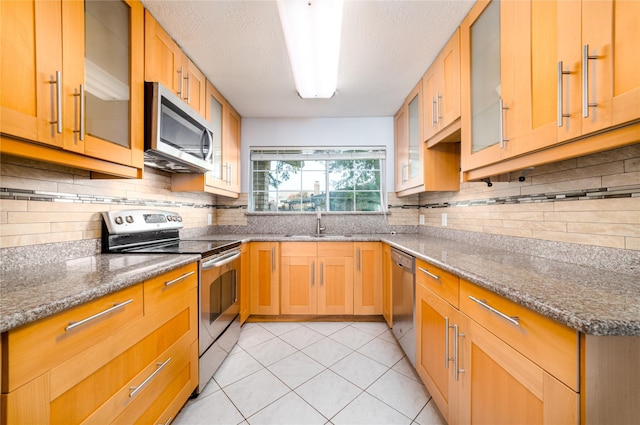 kitchen featuring tasteful backsplash, appliances with stainless steel finishes, sink, and light stone counters