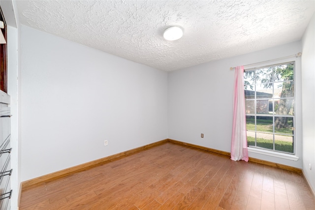 empty room featuring hardwood / wood-style flooring, a healthy amount of sunlight, and a textured ceiling