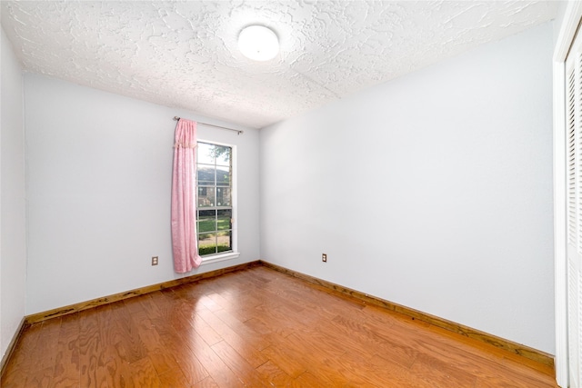 unfurnished room with hardwood / wood-style floors and a textured ceiling