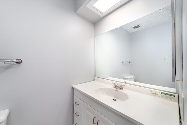 bathroom featuring vanity, toilet, and a skylight