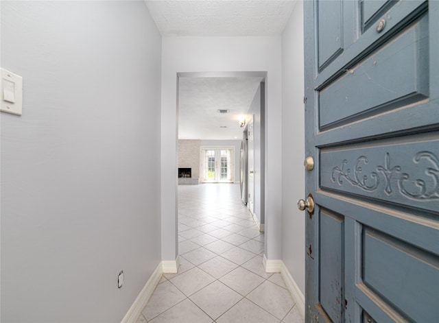 corridor with light tile patterned floors and a textured ceiling