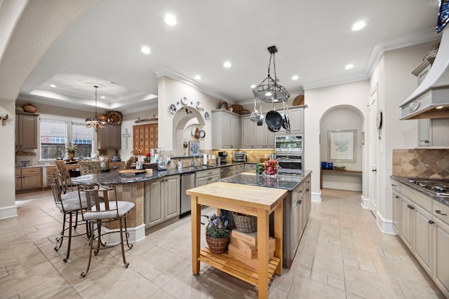 kitchen with a raised ceiling, a center island, pendant lighting, and a kitchen bar