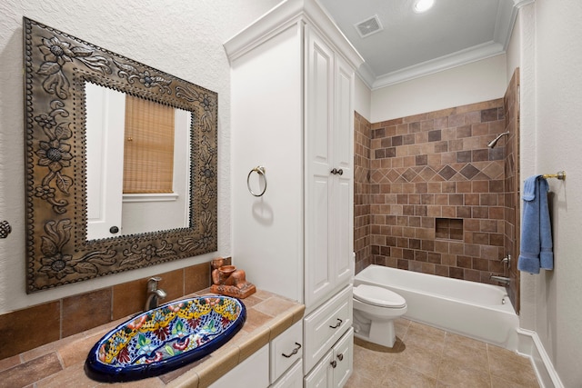 full bathroom featuring tiled shower / bath combo, ornamental molding, tile patterned flooring, vanity, and toilet