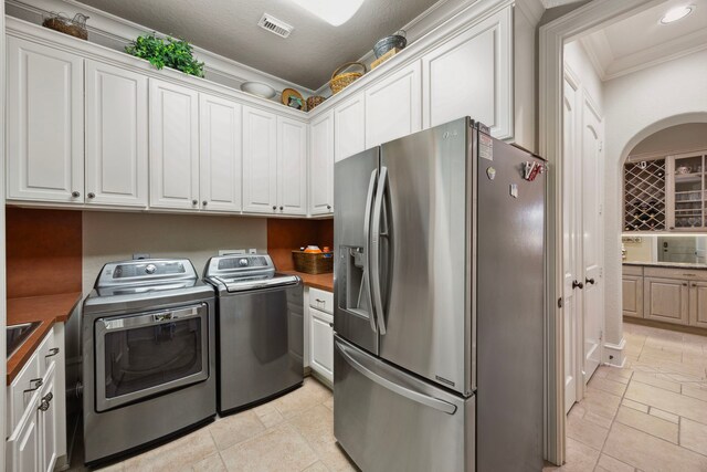 kitchen with butcher block countertops, stainless steel refrigerator with ice dispenser, white cabinets, and washer and clothes dryer