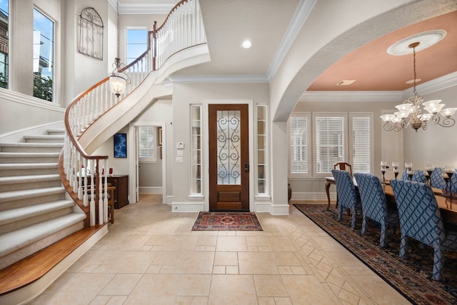 foyer featuring an inviting chandelier, crown molding, and a high ceiling