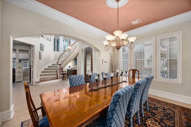 tiled dining area with crown molding and a chandelier