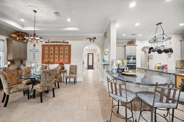 dining area with an inviting chandelier, crown molding, and a raised ceiling