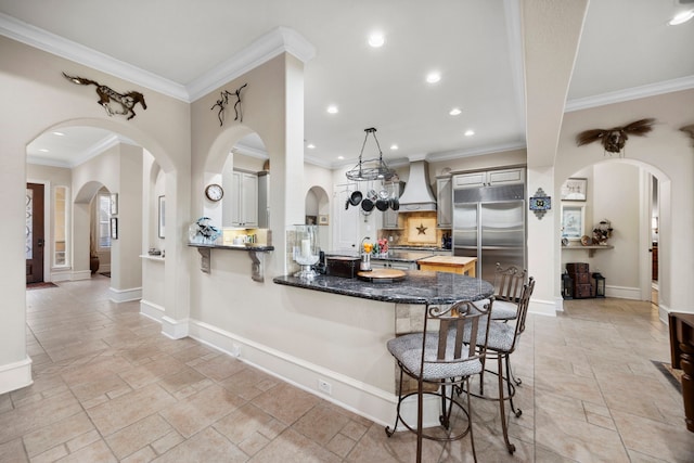 kitchen featuring decorative light fixtures, a breakfast bar area, stainless steel built in fridge, kitchen peninsula, and custom range hood