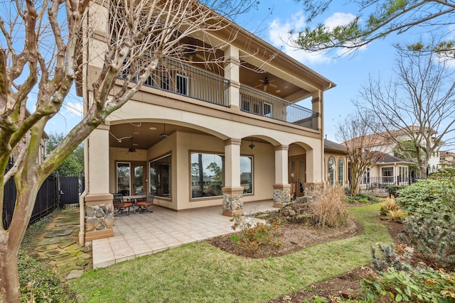 rear view of property with a patio, a balcony, ceiling fan, and a lawn