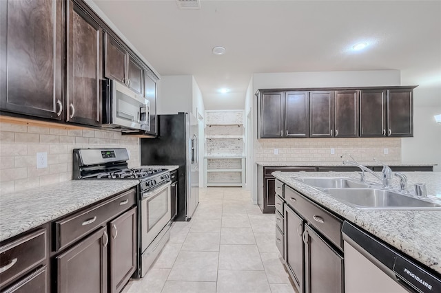 kitchen featuring appliances with stainless steel finishes, sink, decorative backsplash, light tile patterned floors, and dark brown cabinetry